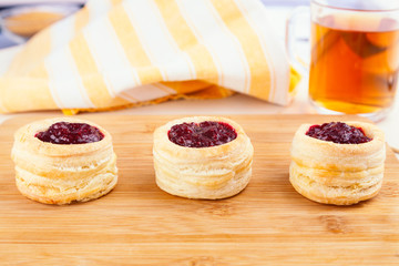 Danish pastry cake with cranberry jam and fresh blueberry and raspberry on the table. Sunny breakfast.