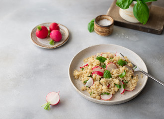 tasty vegetarian salad with quinoa, fresh radish and basil on a gray concrete background. Super food and healthy eating concept. horizontal image. place for text.