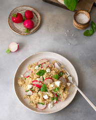 diet salad with quinoa, feta cheese, radish slices and basil in a ceramic plate. healthy food concept. Gray background. vertical image. flat lay