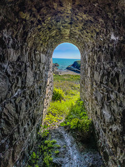 view through a tunnel to a beach and water 