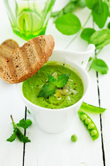 Green pea soup with croutons on wooden rustic background