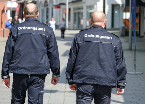 Konzept Ordnung und Sicherheit: Zwei Mitarbeiter des Ordnungsamtes in Uniform auf Streife in der Innenstadt - selektiver Fokus