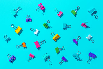 Stationery office clips multicolored, accessories of the secretary on a blue background,hard light.