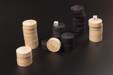 Backgammon. Board game. White dice and white and black chips for playing on a black background. Game for recreation