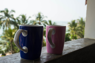 two mugs for hot drinks on a background of palm trees