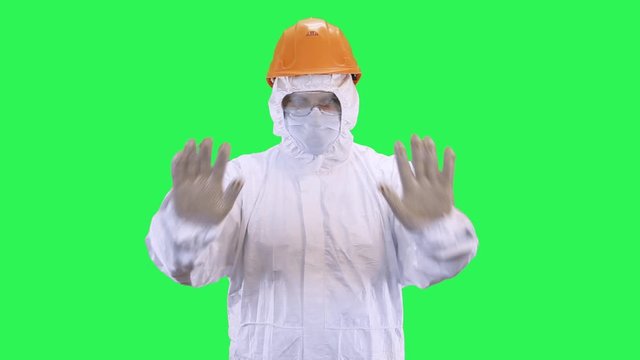 Man in helmet and protective suit shows stop.Green screen background.