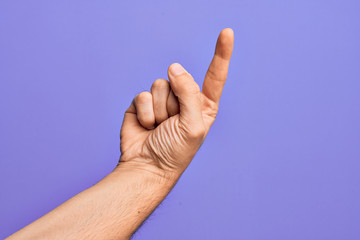 Hand of caucasian young man showing fingers over isolated purple background counting number one using index finger, showing idea and understanding