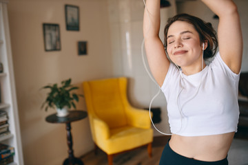 Fototapeta na wymiar People, lifestyle, leisure and technology concept. Happy overjoyed plus sized teenage girl enjoying social distancing, listening to music in earphones, dancing, being carefree and full of energy