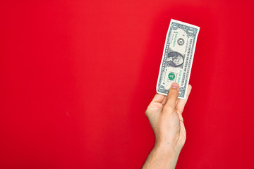 Beautiful hand of man holding one dollar banknote over isolated red background