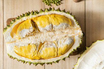 fresh durian, peeled, cut in half, can see bright yellow flesh, appetizing, placed on the wooden floor - top view