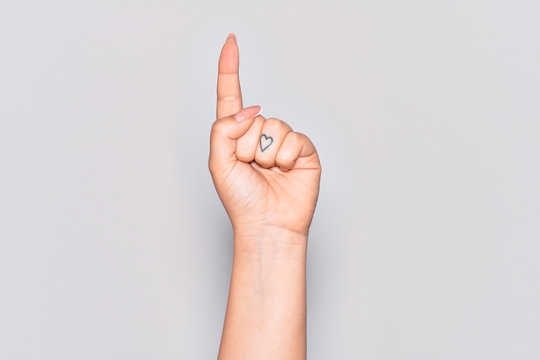 Hand of caucasian young woman counting number one using index finger, showing idea and understanding