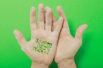 manos con jabón y en la palma de la mano escrito lavarse las manos sobre un fondo verde croma
