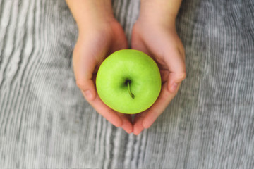Two hands like heart holding a green apple.