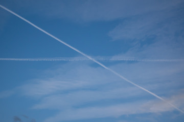 Two traces from planes crossing in the sky blue sky with some thin clouds