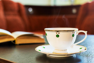 A Cup of coffee and a book on the wooden table.
