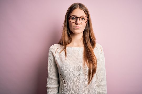 Young beautiful redhead woman wearing casual sweater and glasses over pink background looking sleepy and tired, exhausted for fatigue and hangover, lazy eyes in the morning.