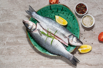 Raw organic sea bass with spices, herbs and vegetables on the marble table ready to cook. Sea food concept. Healthy and organic food concept.