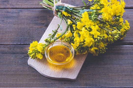 a cup with rapeseed oil next to it are rapeseed flowers on a plate