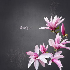 Floral card with copy space. Pink magnolia flowers on dark textured background.