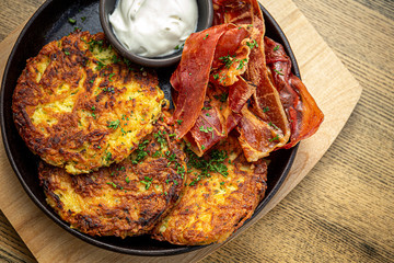 Potato pancakes with cooked bacon, sour cream