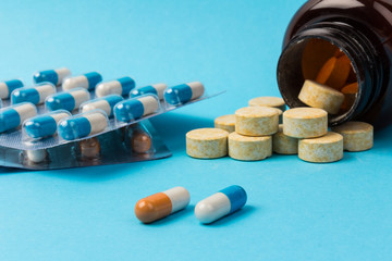 Pills isolated on blue background. Medical drug capsule. Concept of coronavirus