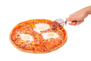 Tasty pizza with beef sausages, eggs and bacon or Brunch pizza. Man's hand with a pizza cutter cut...