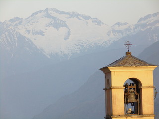 Campanile chiesa cattolica con sfondo valle montagne innevate