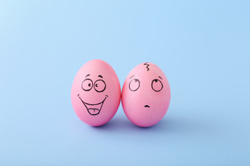 Funny pink eggs with face feeling on blue background