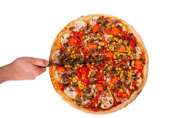 Man's hand with a knife cut the pizza with mushrooms, corn, cherry tomatos, courgettes and bell peppers or Veggie Vegetarian pizza. Isolation on white background with clipping path, top view