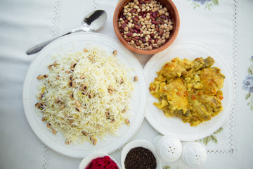 Khan pilaf in a pita . Dry beans on top of pilaf . Dry beans in a brown bowl . Chicken curry on the white plate . red cabbage sauerkraut and black pepper in a small bowl . Shah pilaf on the plate.