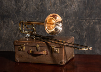 Musical instrument trombone lies on an old suitcase