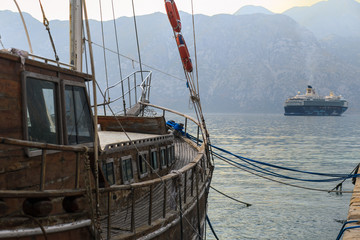 Old ship moored to the shore against the background of a large liner