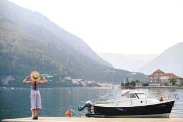 A girl stands on the pier, her back to us. Beautiful place - Kotor Bay