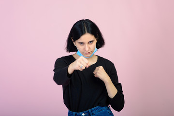The caucasian girl in blue colored protective face mask. The girl looking at camera. Portrait shot over pink background. virus and pollution protection concept.