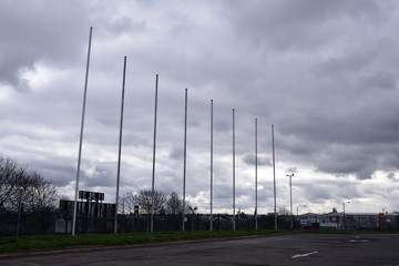Fototapeta na wymiar Tall Bare Metal Flag Poles in Car Park of Retail Store 