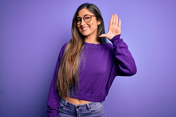 Obraz na płótnie Canvas Young beautiful smart woman wearing glasses over purple isolated background Waiving saying hello happy and smiling, friendly welcome gesture