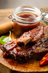 Delicious BBQ baby-back ribs with tangy sauce and a basting brush on wooden cutting board