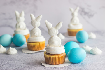 Cute easter composition. Blue easter eggs, meringue easter bunnies and raisin carrot muffins