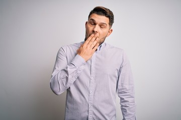 Young business man with blue eyes standing over isolated background bored yawning tired covering mouth with hand. Restless and sleepiness.
