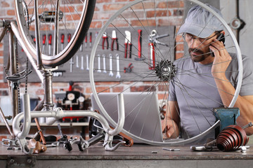 man repair the vintage bicycle with mobile phone at the computer search spare parts on the internet...