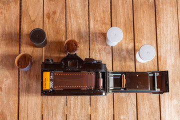 top view of an old analog camera with film strips and film containers around it