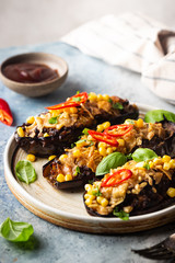 Baked aubergines boats, stuffed with minced meat, tomatoes, corn, garlic and cheese in white plate