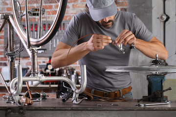 man repair the vintage bicycle in garage workshop on the workbench with tools, diy concept