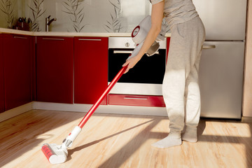 Woman cleaning house with wireless vacuum cleaner.