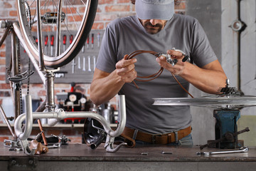 man repair the vintage bicycle in garage workshop on the workbench with tools, diy concept