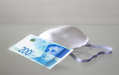 Protective mask and banknote of 200 shekels as a symbol of fine for lack of protective mask in...