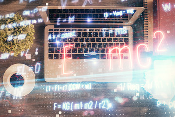 Physics and math theme hologram with formula drawings over computer on the desktop background. Top view. Multi exposure. Concept of education.