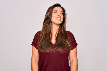Fototapeta premium Young hispanic woman wearing casual t-shirt standing over isolated background looking away to side with smile on face, natural expression. Laughing confident.
