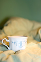 Fototapeta na wymiar Tea in a vintage porcelain cup on a bed. Selective focus.