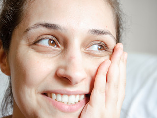 Young latin woman smiling with hand on her face